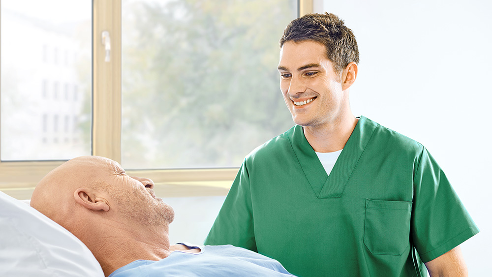A nurse is talking with a patient at the bedside